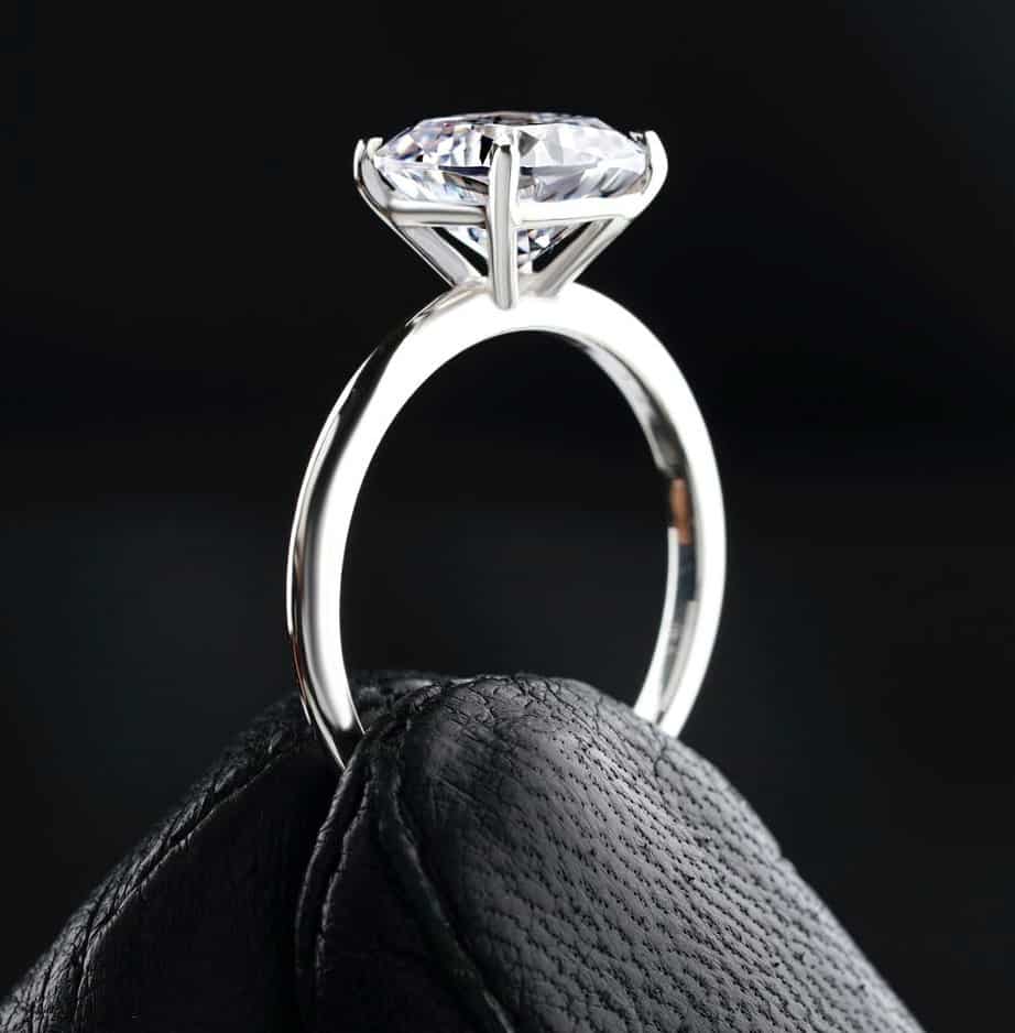 Solitaire engagement diamond ring held with leather gloves